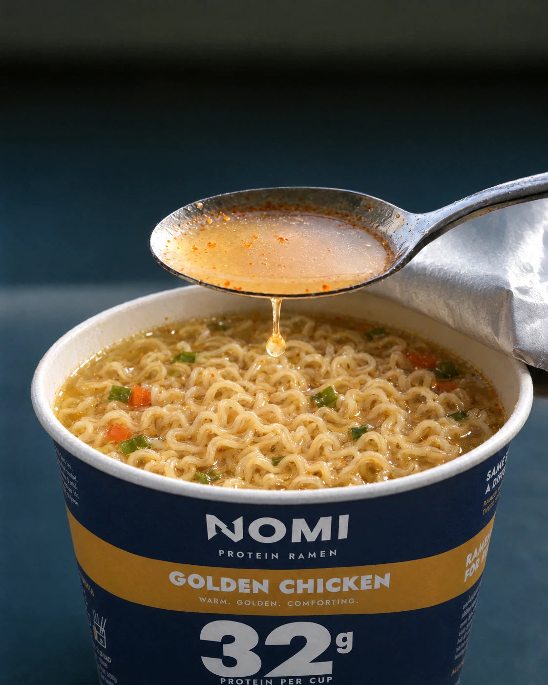 A spoonful of Golden Chicken broth lifted over the noodles