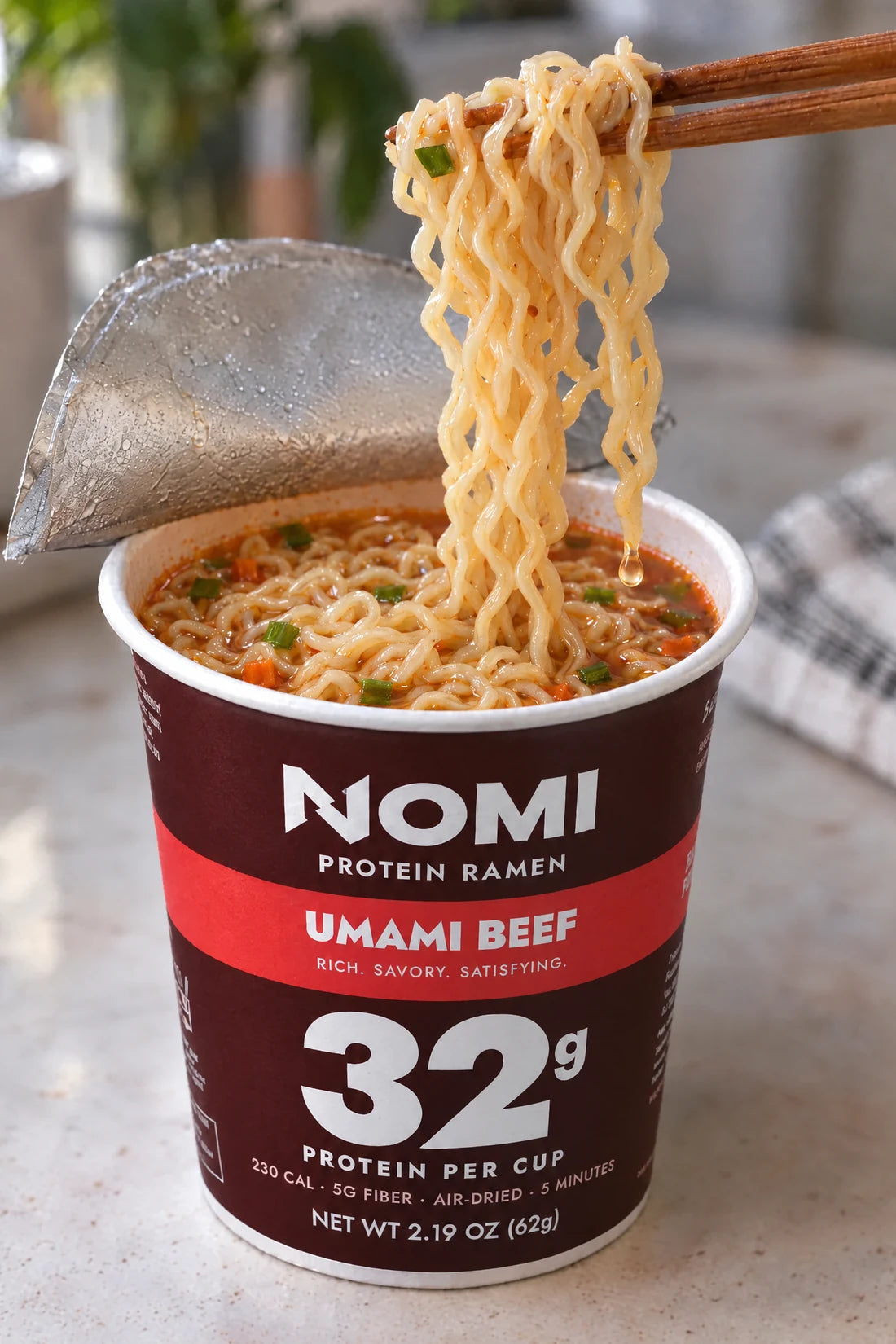 Chopsticks lifting noodles from a NOMI cup