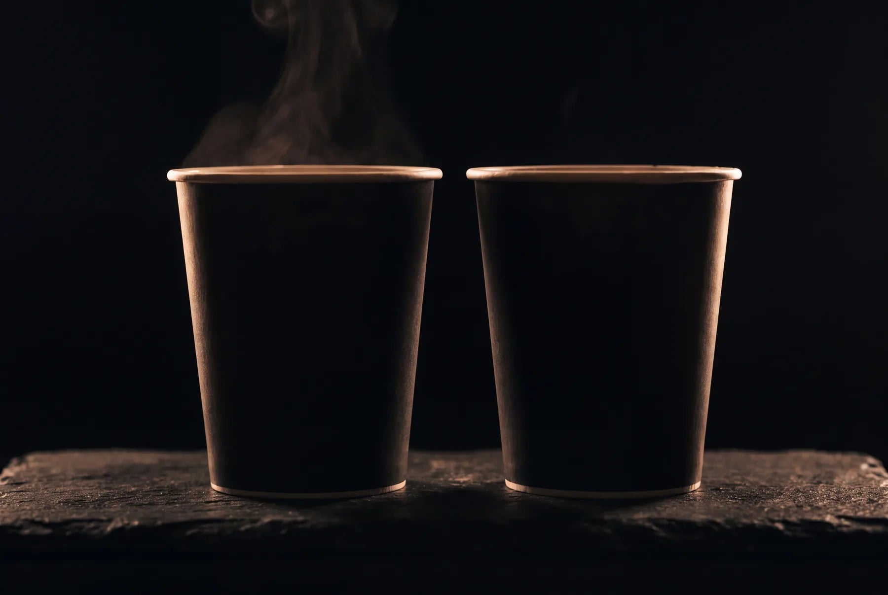 Two unlabeled NOMI cups in shadow — the next flavors